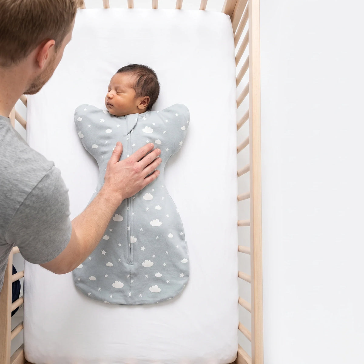 Newborn laid on their back on a bare firm crib surface in the LIOR Held Swaddle Sack.